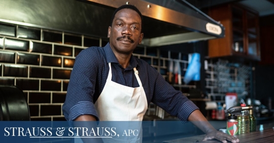 African American business owner leaning over a counter and wearing an apron